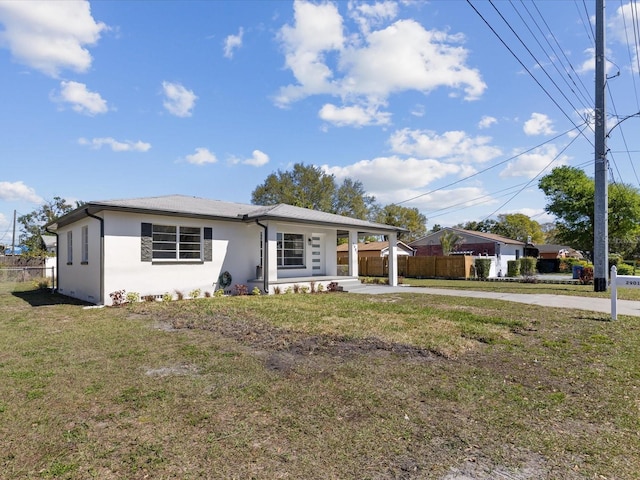 view of front of house featuring fence, driveway, a front lawn, and stucco siding