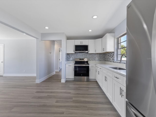 kitchen featuring a sink, stainless steel appliances, light countertops, light wood-type flooring, and backsplash