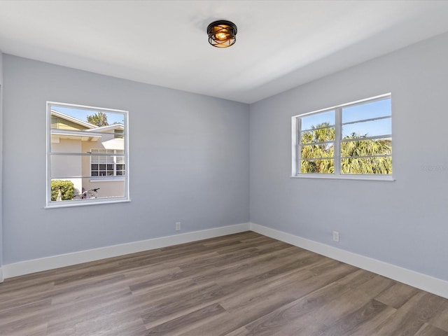 unfurnished room with plenty of natural light, baseboards, and wood finished floors