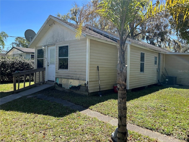 view of side of property with entry steps, central AC, and a yard