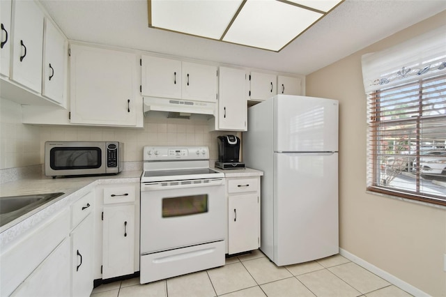 kitchen with white appliances, tasteful backsplash, white cabinets, under cabinet range hood, and light tile patterned flooring