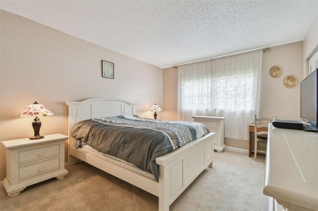 bedroom featuring light carpet and a textured ceiling