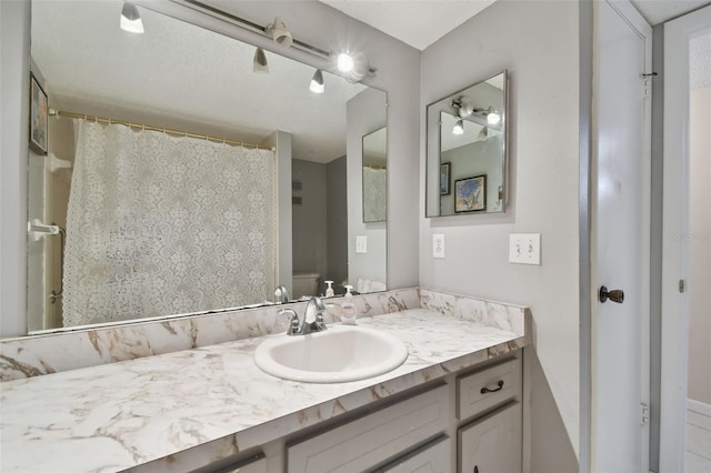 bathroom featuring curtained shower, vanity, and toilet