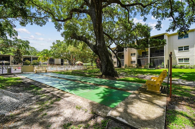 view of property's community with fence and shuffleboard