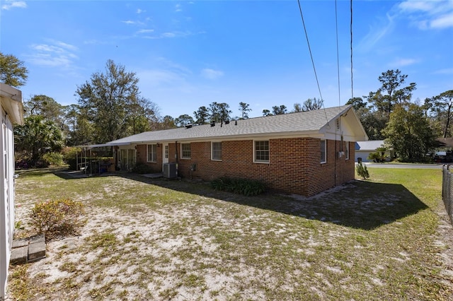 back of property featuring brick siding, a yard, and central air condition unit