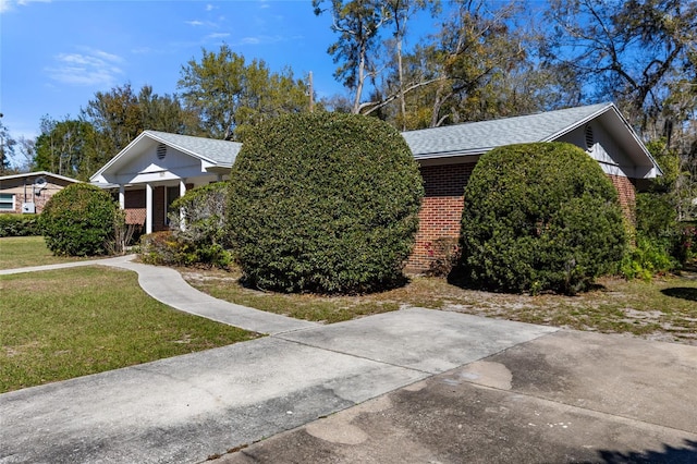 view of property hidden behind natural elements with a front yard and brick siding