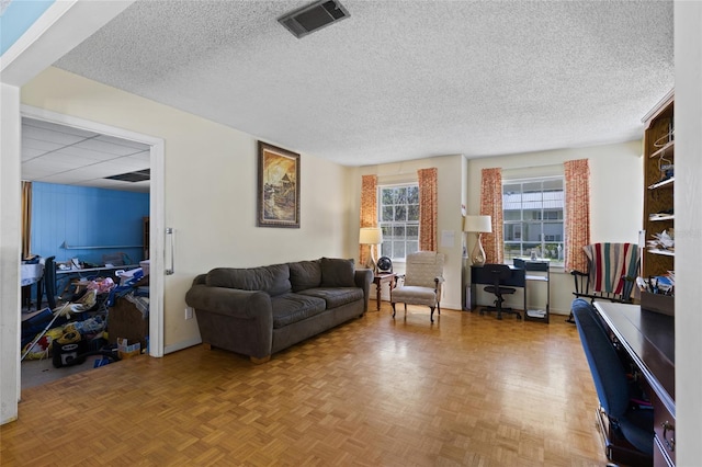 living room with a textured ceiling, visible vents, and baseboards