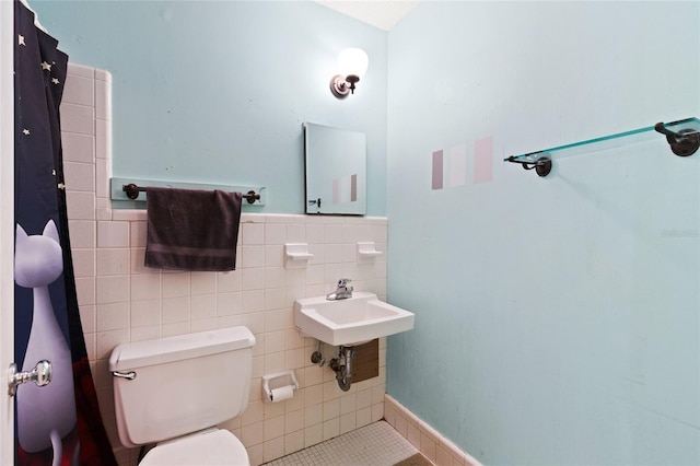 full bathroom with toilet, tile walls, and wainscoting