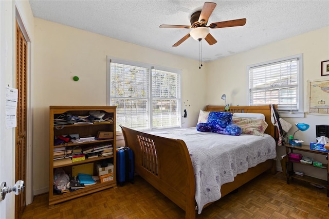 bedroom featuring a textured ceiling, ceiling fan, and multiple windows