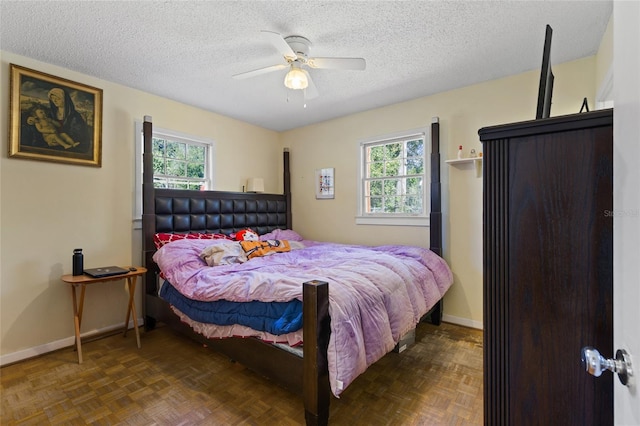 bedroom with a ceiling fan, baseboards, and a textured ceiling