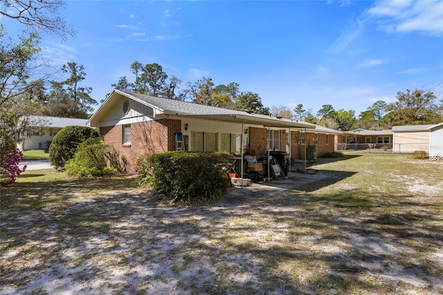 rear view of house featuring brick siding, a yard, and fence