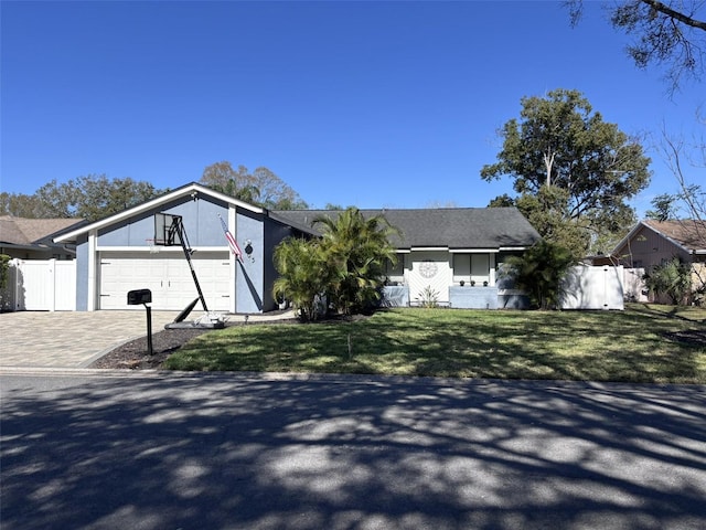 view of front of house featuring a front lawn, fence, decorative driveway, a garage, and a gate