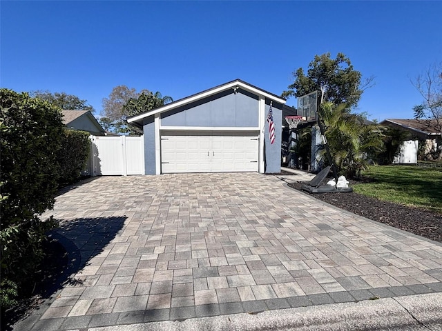 garage with a gate, decorative driveway, and fence