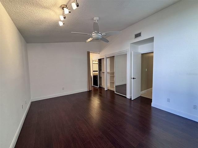 interior space with a ceiling fan, wood finished floors, visible vents, vaulted ceiling, and a textured ceiling