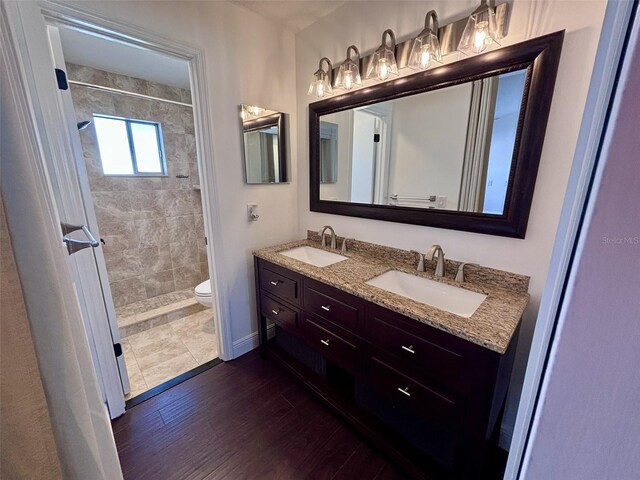 bathroom featuring double vanity, toilet, wood finished floors, and a sink