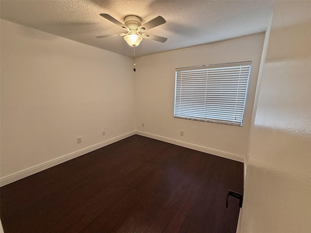 unfurnished room featuring baseboards, a textured ceiling, and dark wood finished floors