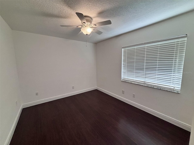 spare room featuring a textured ceiling, baseboards, dark wood-style flooring, and ceiling fan