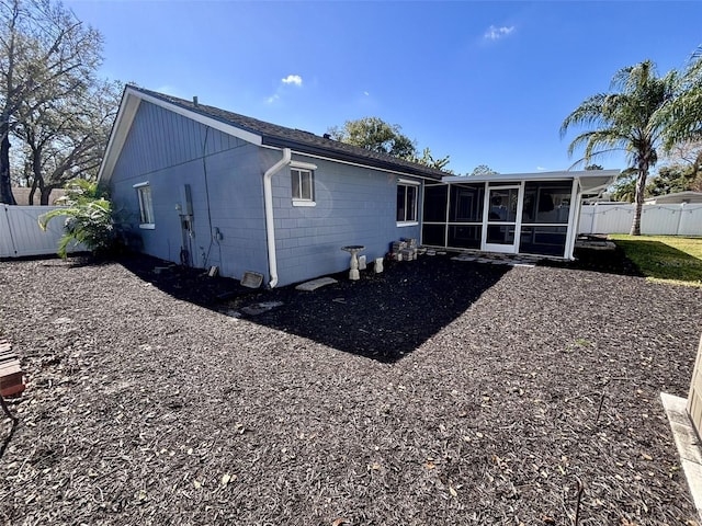 back of house featuring fence, concrete block siding, and a sunroom