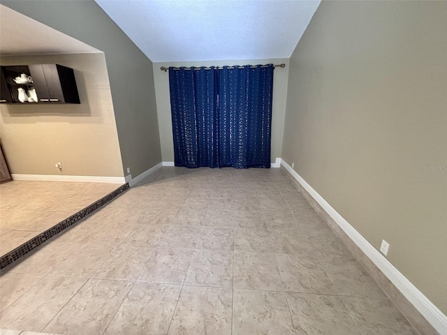 unfurnished room with lofted ceiling and baseboards