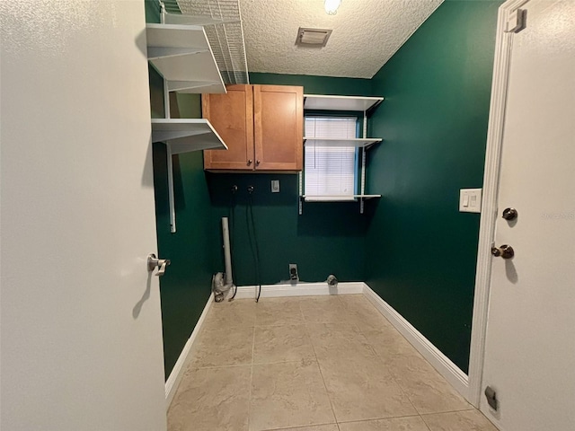 clothes washing area featuring visible vents, cabinet space, baseboards, and a textured ceiling