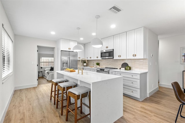 kitchen with visible vents, appliances with stainless steel finishes, a kitchen breakfast bar, and decorative backsplash