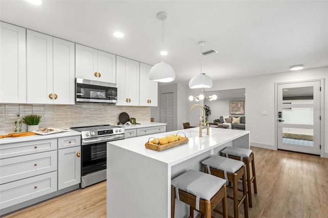 kitchen with visible vents, decorative backsplash, appliances with stainless steel finishes, a breakfast bar area, and light countertops