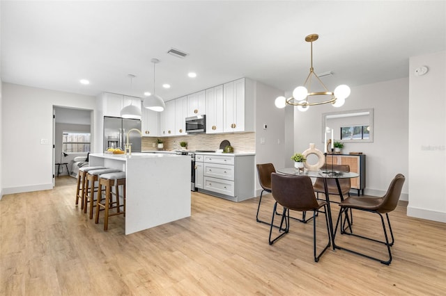 kitchen featuring light wood-style flooring, visible vents, light countertops, appliances with stainless steel finishes, and backsplash