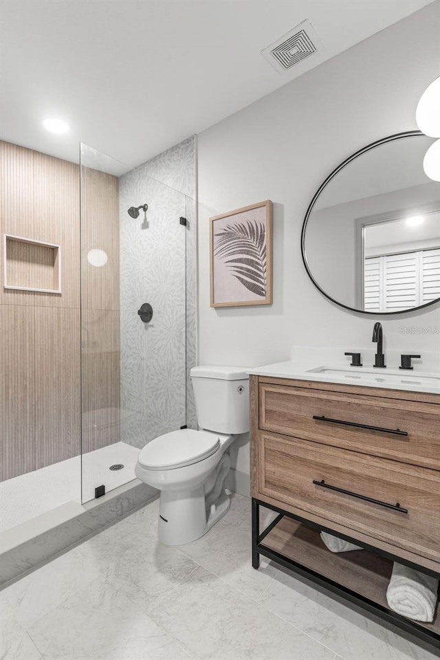 bathroom with visible vents, a tile shower, vanity, and toilet