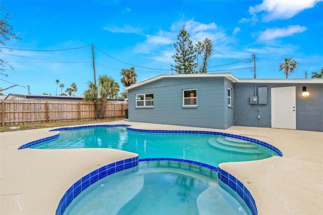 view of swimming pool featuring a patio, fence, and a pool with connected hot tub