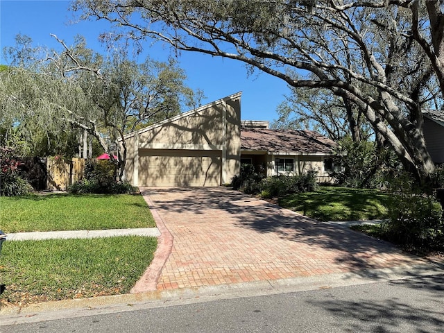 view of front of home with a garage, fence, a front lawn, and decorative driveway