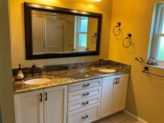 full bath featuring tile patterned flooring, a sink, baseboards, and double vanity