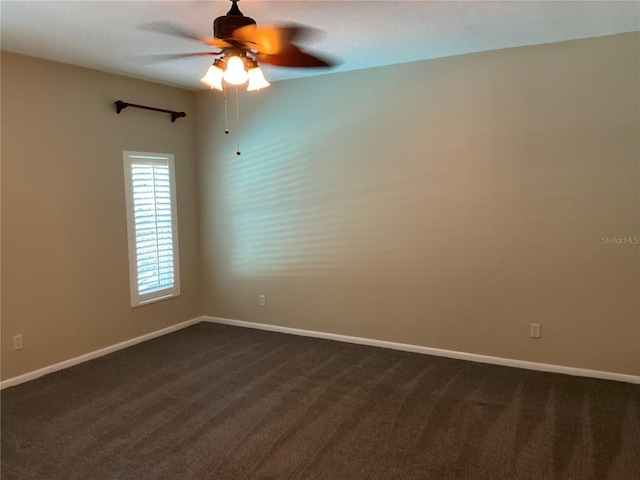 unfurnished room featuring dark carpet, a ceiling fan, and baseboards