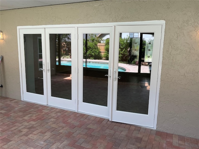 doorway featuring brick floor, french doors, and a textured wall