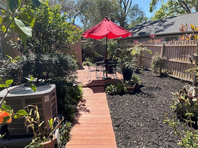 view of yard with outdoor dining space, a fenced backyard, a deck, and central air condition unit