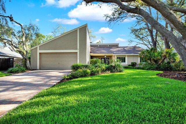 11712 Palmer Dr, Tampa, FL 33624 - mid-century home featuring decorative driveway, a garage, a front lawn, and stucco siding