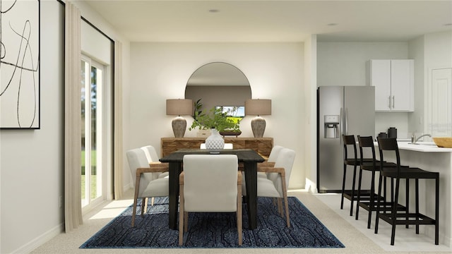 dining space featuring light carpet and baseboards