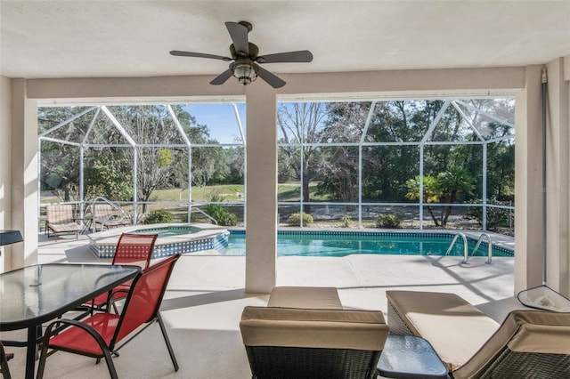 view of swimming pool featuring glass enclosure, ceiling fan, a pool with connected hot tub, and a patio