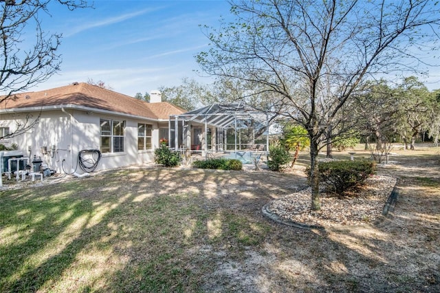 rear view of property featuring a lanai, a chimney, and a yard