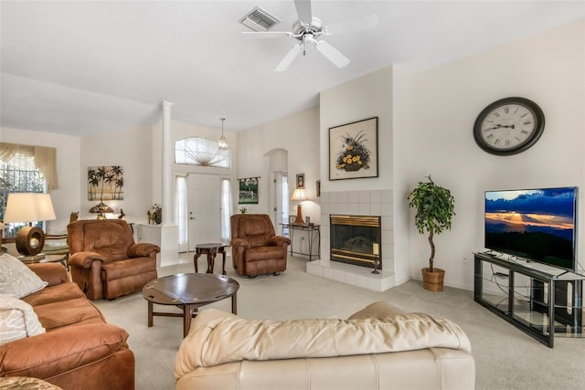 living room with ceiling fan, arched walkways, light colored carpet, a fireplace, and visible vents