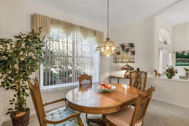 carpeted dining room with a chandelier and baseboards