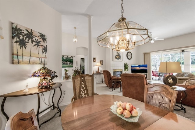 dining room with a chandelier, carpet, a fireplace, and arched walkways