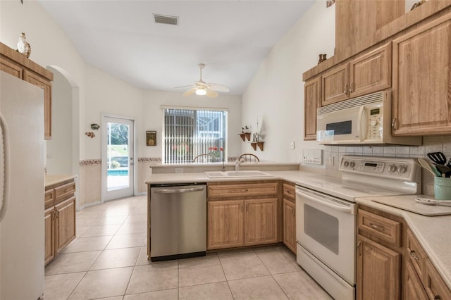 kitchen with light countertops, light tile patterned flooring, a sink, white appliances, and a peninsula