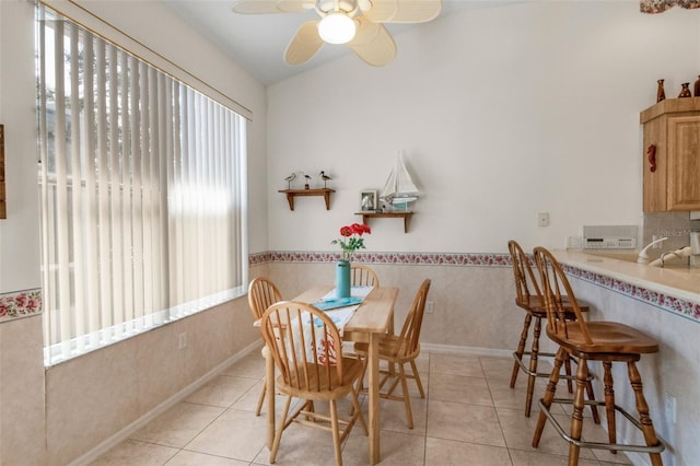 dining space with ceiling fan, wainscoting, and light tile patterned flooring