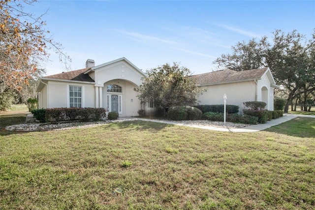 ranch-style home with a front yard, a chimney, and stucco siding