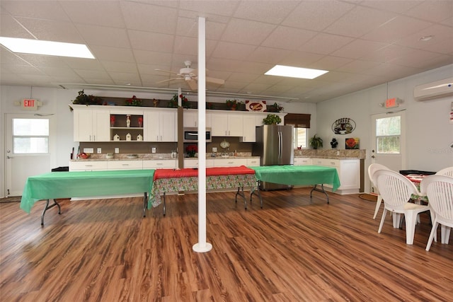 recreation room with ceiling fan, a wall mounted air conditioner, plenty of natural light, and wood finished floors