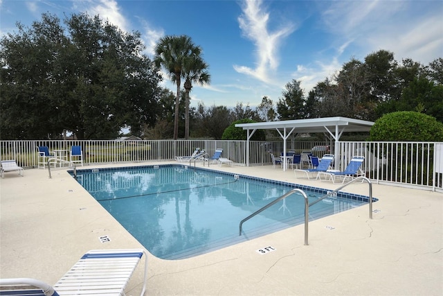 community pool with a patio area and fence