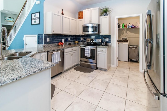 kitchen with backsplash, light tile patterned floors, appliances with stainless steel finishes, and a sink