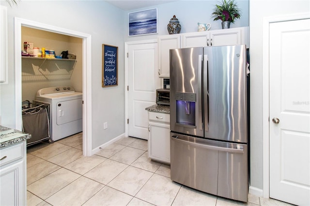 kitchen featuring light tile patterned floors, baseboards, washer / dryer, stainless steel fridge with ice dispenser, and white cabinets