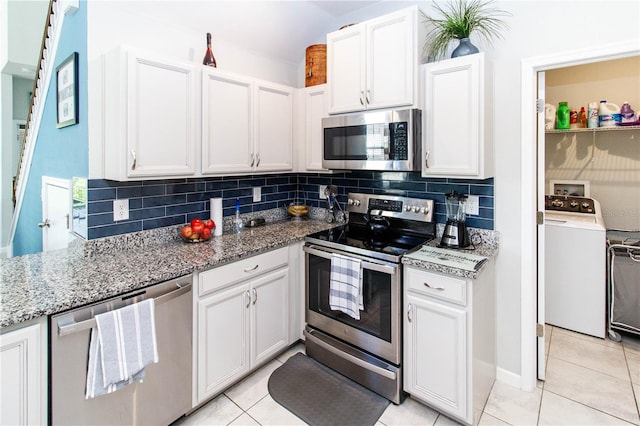 kitchen featuring light stone countertops, washer / clothes dryer, stainless steel appliances, white cabinetry, and backsplash