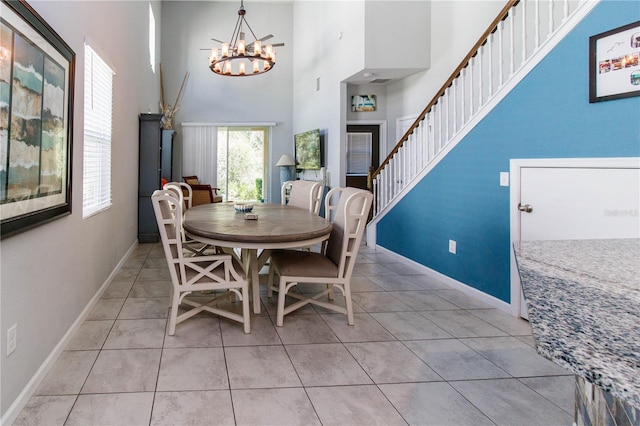 dining area with light tile patterned flooring, baseboards, a high ceiling, and an inviting chandelier